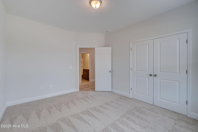 unfurnished bedroom with carpet floors, a closet, and baseboards