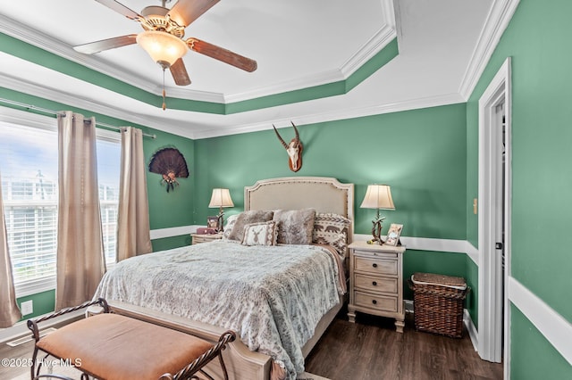 bedroom featuring ornamental molding, dark wood finished floors, a ceiling fan, and a raised ceiling