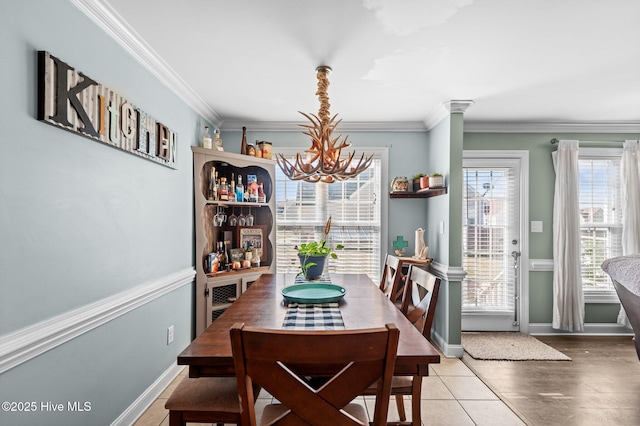 dining room featuring ornate columns, a notable chandelier, baseboards, and crown molding