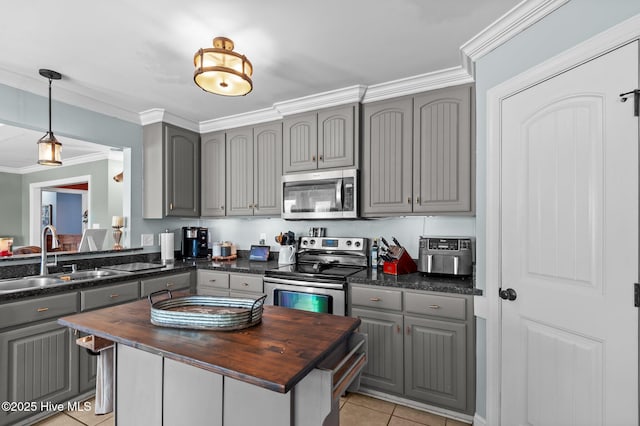 kitchen featuring wood counters, appliances with stainless steel finishes, a sink, and gray cabinetry