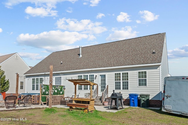 rear view of house with entry steps, a yard, a patio, and roof with shingles