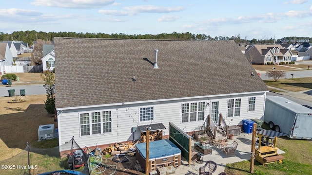 back of house with entry steps, a patio, a residential view, roof with shingles, and fence