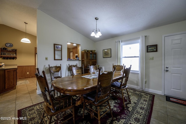 dining space featuring light tile patterned floors, a chandelier, a textured ceiling, and vaulted ceiling