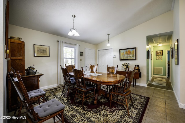 tiled dining room featuring vaulted ceiling, attic access, baseboards, and visible vents