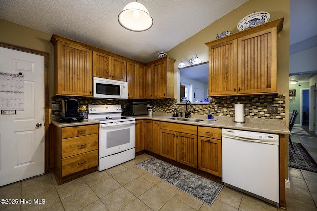 kitchen featuring brown cabinets, a sink, backsplash, white appliances, and light tile patterned flooring