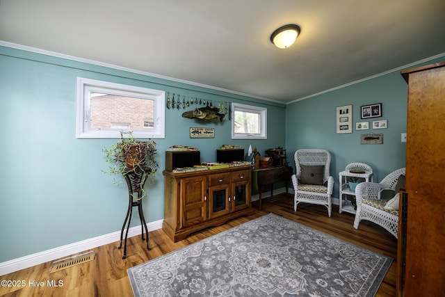 office space with visible vents, crown molding, baseboards, and wood finished floors