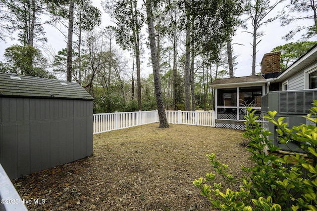 view of yard with an outdoor structure, a shed, a fenced backyard, and a sunroom