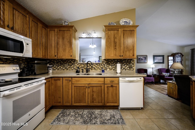 kitchen featuring open floor plan, vaulted ceiling, light tile patterned floors, white appliances, and a sink