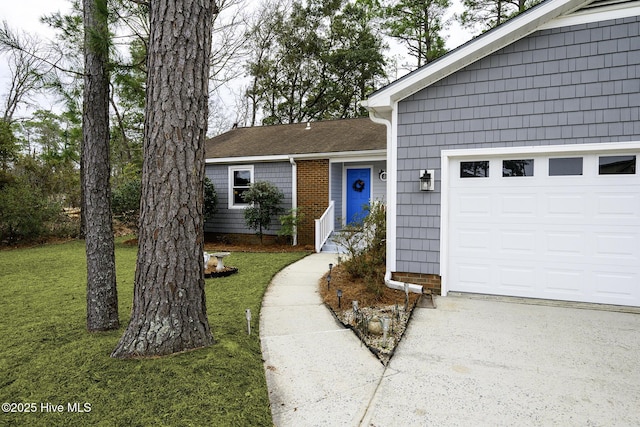 property entrance featuring brick siding, a lawn, a garage, and driveway