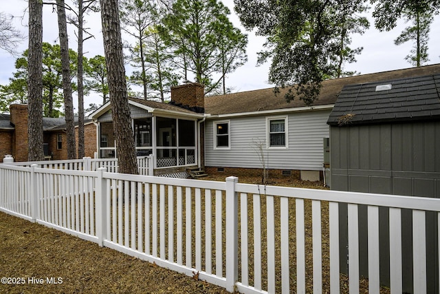 back of property with fence, a chimney, an outdoor structure, a sunroom, and crawl space