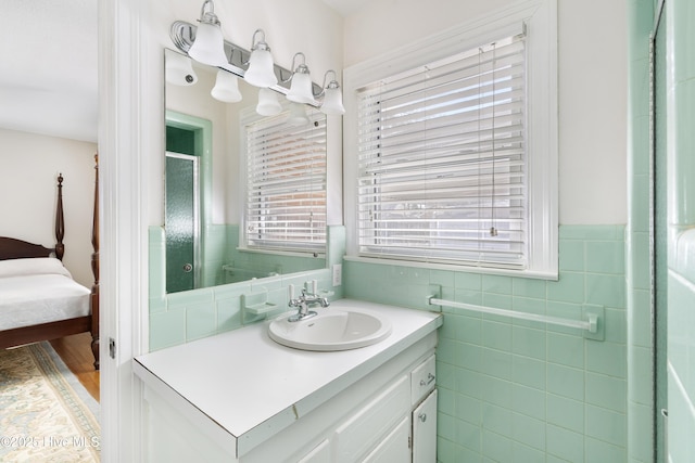 ensuite bathroom featuring a wainscoted wall, ensuite bath, vanity, and tile walls