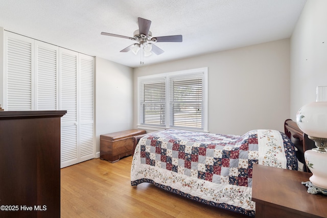 bedroom with a closet, ceiling fan, light wood-style flooring, and a textured ceiling