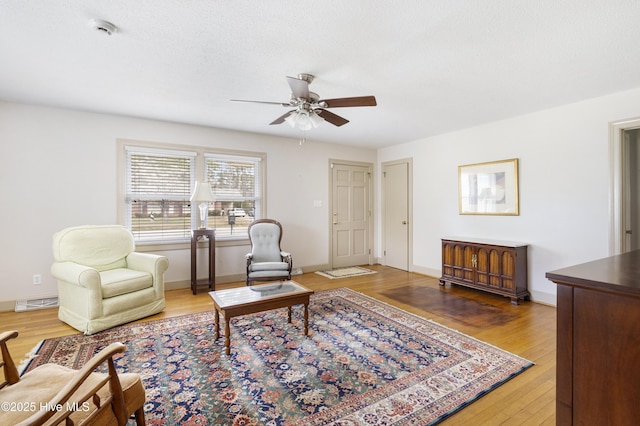 living room with ceiling fan, baseboards, and wood finished floors