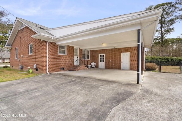 view of front of home featuring brick siding, entry steps, crawl space, a carport, and driveway