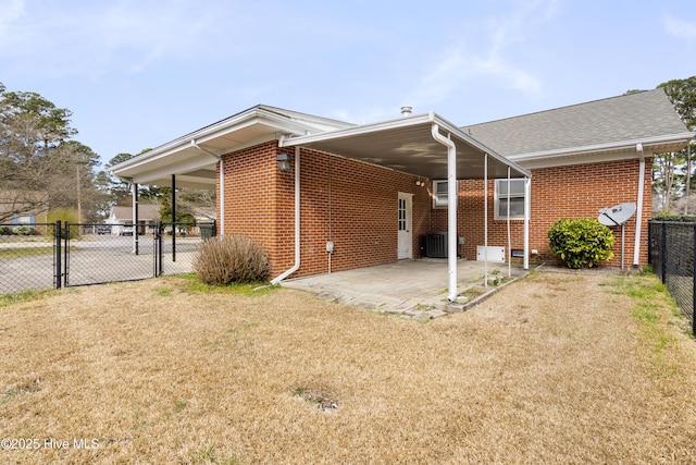 back of property with a gate, fence, a yard, a patio area, and brick siding