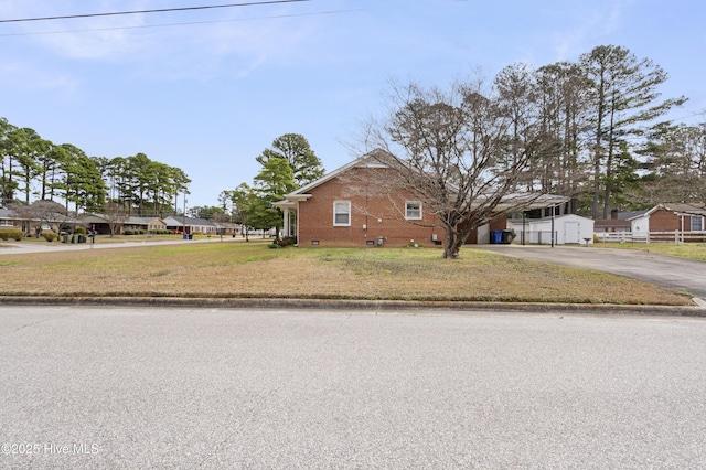 view of side of home with crawl space, brick siding, a yard, and driveway