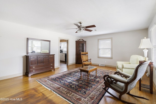 living area featuring baseboards, a ceiling fan, and light wood-style floors