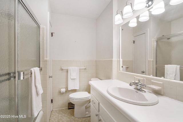 full bath featuring toilet, a wainscoted wall, a shower with shower door, vanity, and tile walls