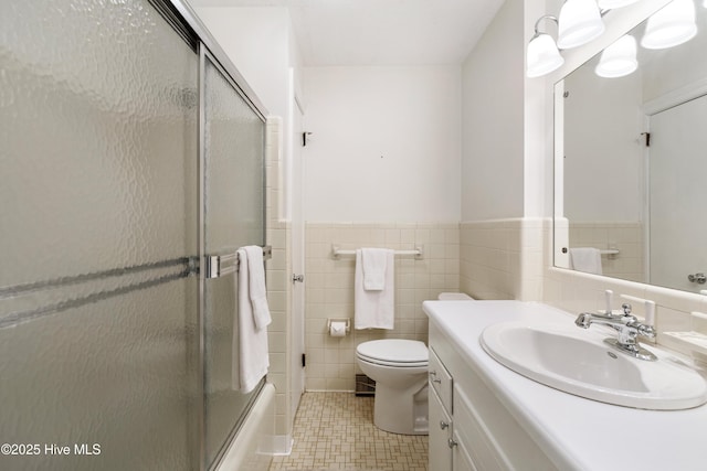 full bathroom with wainscoting, toilet, tile walls, and vanity