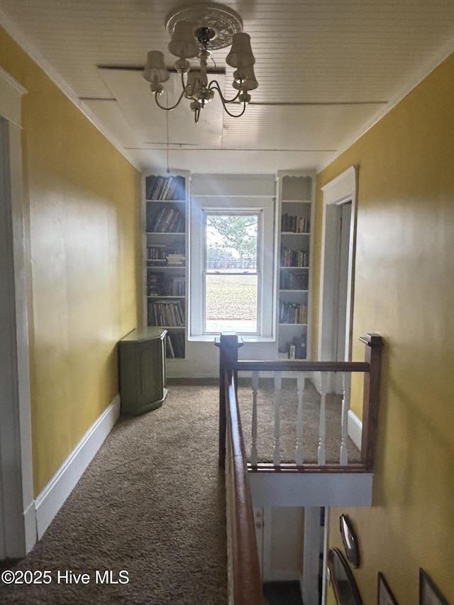 hall with carpet flooring, a notable chandelier, and baseboards