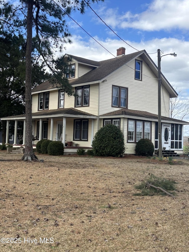 view of front of home featuring covered porch, a chimney, and a sunroom