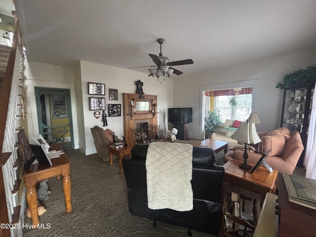 living room featuring ceiling fan, a tiled fireplace, and carpet flooring