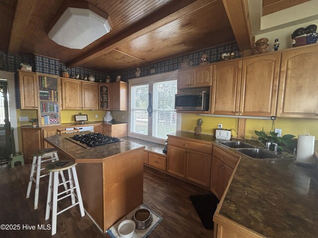 kitchen with appliances with stainless steel finishes, a center island, dark wood-type flooring, and a sink