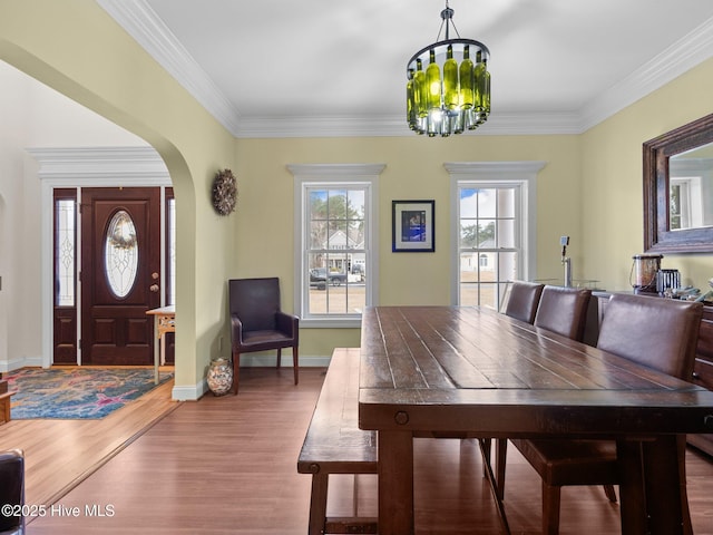 dining room with wood finished floors, a notable chandelier, a healthy amount of sunlight, and arched walkways