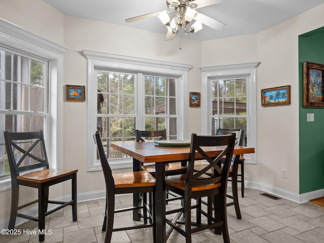 dining area with stone tile flooring, visible vents, baseboards, and a ceiling fan