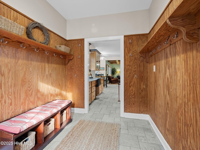 mudroom featuring wooden walls, baseboards, and stone finish floor