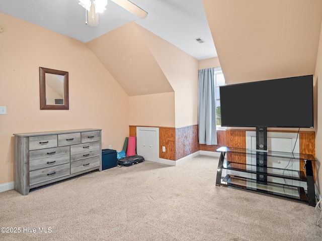 interior space featuring visible vents, wainscoting, ceiling fan, and vaulted ceiling