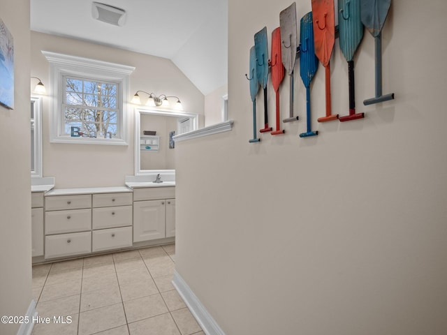 bathroom featuring tile patterned flooring, vaulted ceiling, vanity, and baseboards