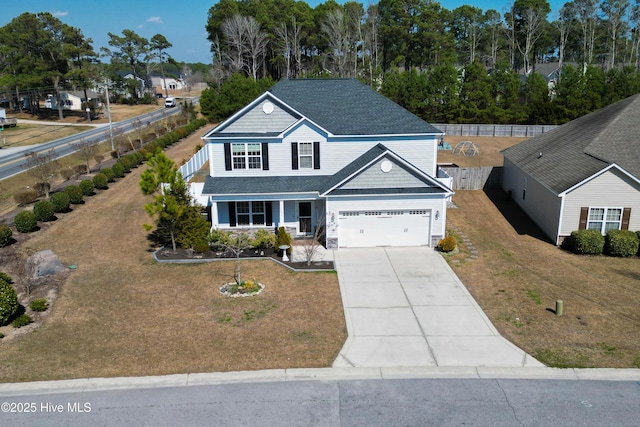 traditional-style house featuring driveway, fence, and a front yard