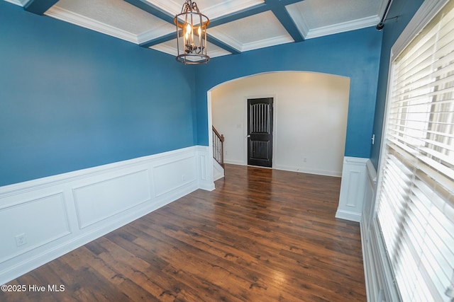 unfurnished room featuring arched walkways, wood finished floors, coffered ceiling, and stairs