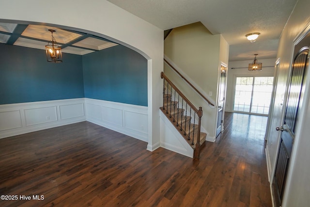 interior space with stairs, dark wood-style flooring, coffered ceiling, and a chandelier