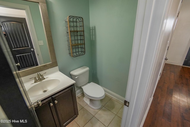 half bathroom featuring tile patterned flooring, vanity, toilet, and baseboards