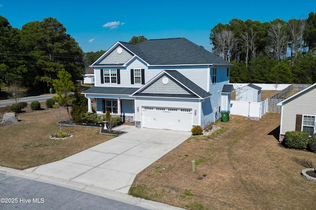 view of front of house featuring concrete driveway, a gate, fence, a garage, and a front lawn