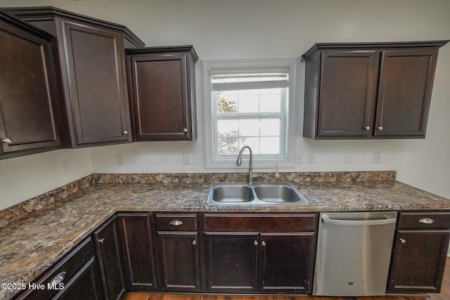 kitchen featuring stainless steel dishwasher, dark countertops, a sink, and dark brown cabinetry