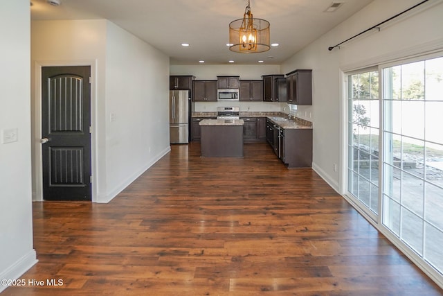 kitchen featuring recessed lighting, a sink, dark brown cabinets, appliances with stainless steel finishes, and a center island