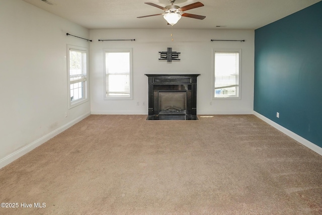 unfurnished living room featuring a fireplace with flush hearth, carpet flooring, plenty of natural light, and baseboards