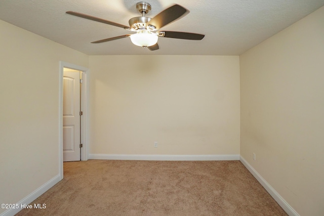 unfurnished room with a textured ceiling, baseboards, and light colored carpet