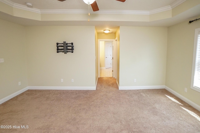 empty room featuring ornamental molding, a tray ceiling, carpet flooring, and baseboards