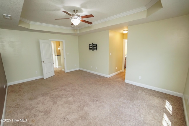 empty room featuring baseboards, ornamental molding, a raised ceiling, and light colored carpet