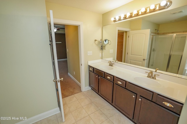 full bathroom with double vanity, a stall shower, tile patterned flooring, and a sink