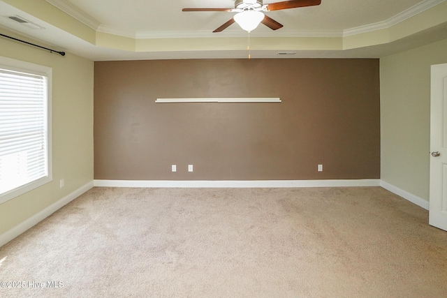 carpeted empty room with visible vents, baseboards, a ceiling fan, a raised ceiling, and crown molding