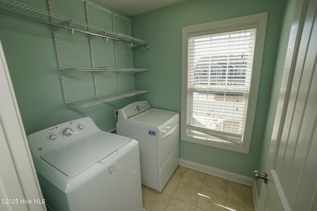 clothes washing area with laundry area, washing machine and dryer, light tile patterned floors, and baseboards