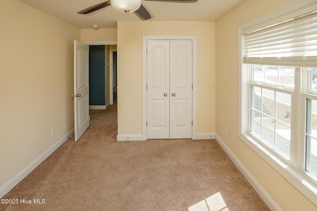 unfurnished bedroom with baseboards, a closet, a ceiling fan, and light colored carpet