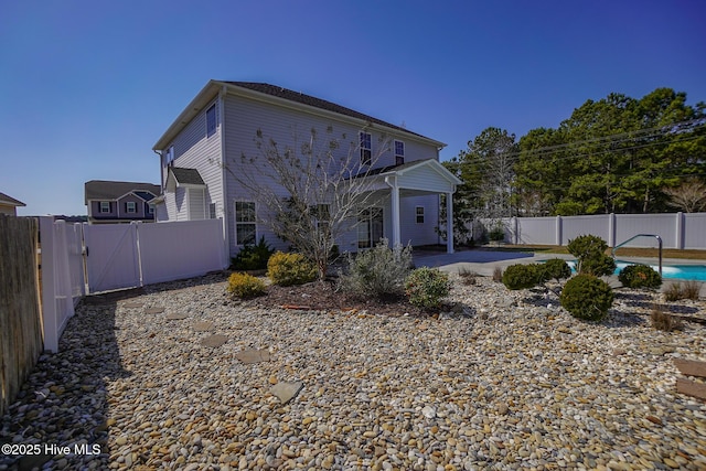 rear view of property featuring a patio area, a fenced backyard, and a fenced in pool