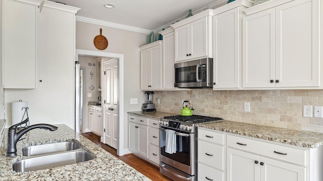 kitchen featuring a sink, white cabinets, ornamental molding, appliances with stainless steel finishes, and decorative backsplash