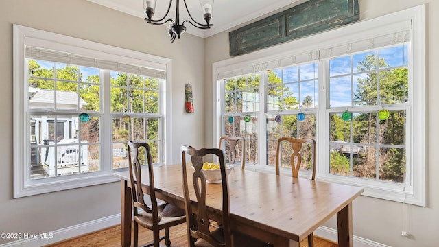 dining space with a chandelier, crown molding, baseboards, and wood finished floors